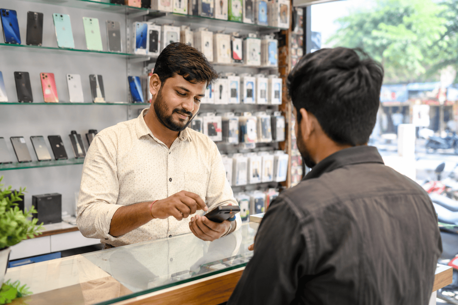 Electronics store owner using BillClap GST billing software at the counter